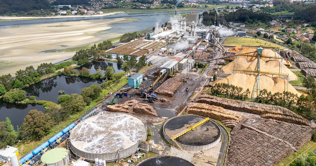 Expansive outdoor pulp mill woodyard with massive log piles, monitored by Syn-Fab camera systems