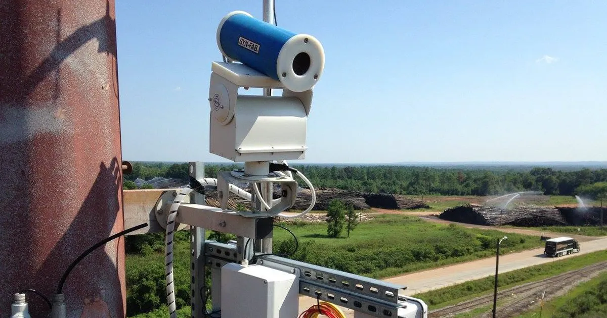 Syn-Fab Sentinel SF30 camera mounted high on a pole monitoring a log pile being sprayed with water in a pulp mill woodyard