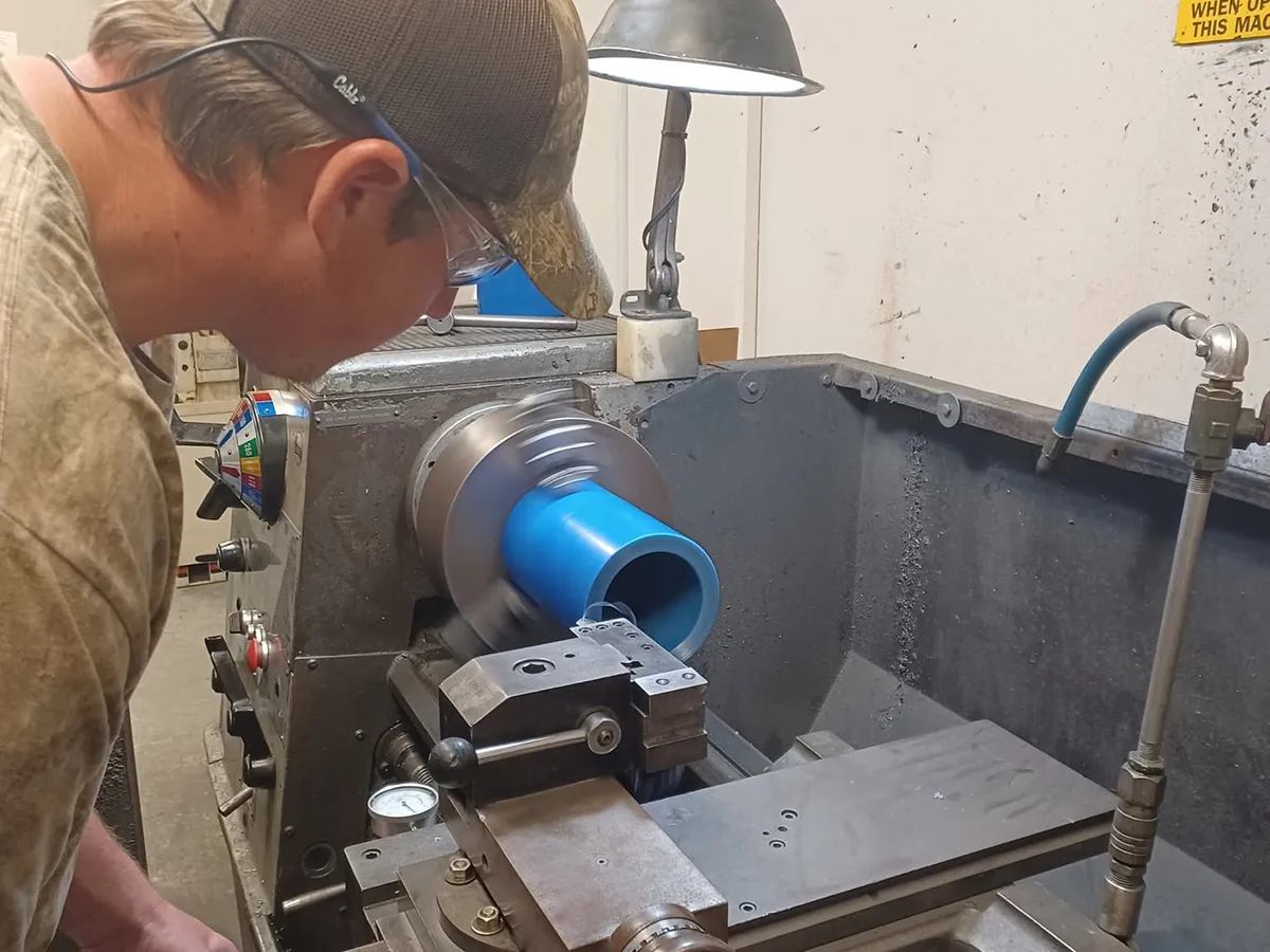 Syn-Fab machinist manufacturing a custom high-temperature camera enclosure on a lathe at our Mobile, Alabama facility.